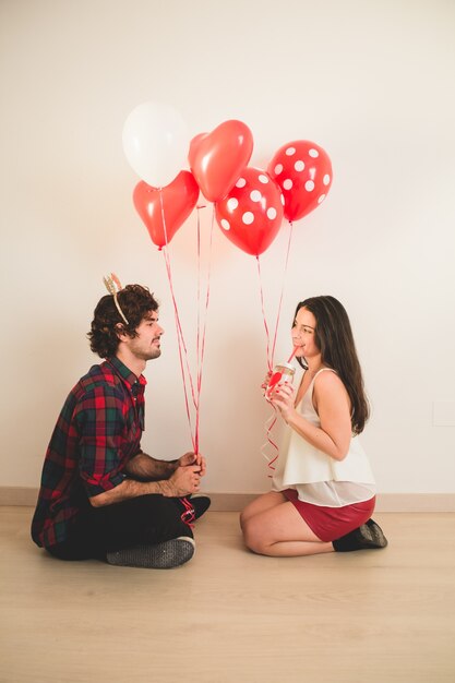 Couple sitting on the floor with balloons in hand