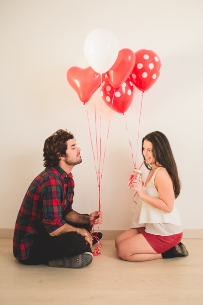 Couple sitting on the floor with balloons in hand