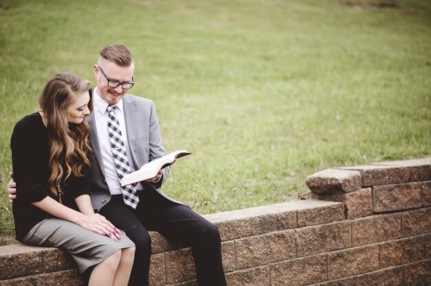 Пара сидит в саду и вместе с любовью читает книгу