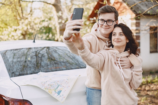 Free photo couple sitting on a hood of car in a park