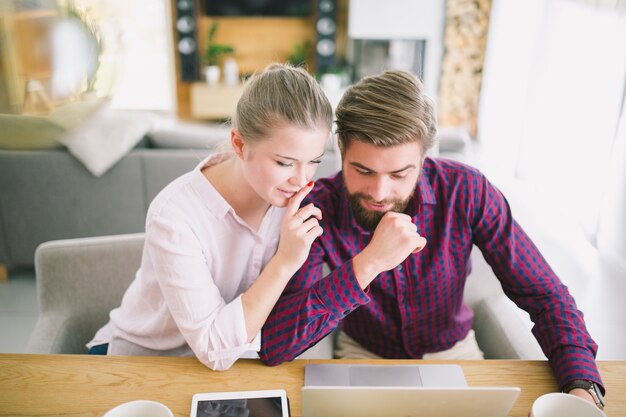 Couple sitting at laptop at home