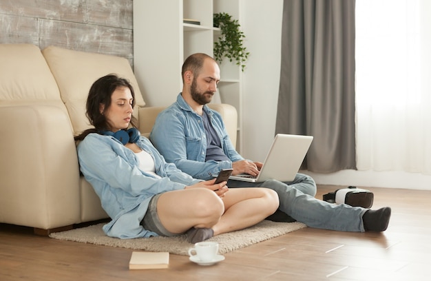 Пара, сидя на ковре в гостиной, просматривает Интернет