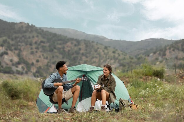 Couple sitting near tent full shot