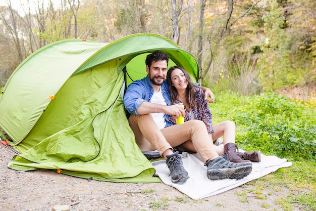 Free photo couple sitting near tent