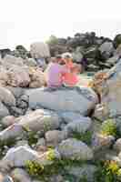 Free photo couple sitting on rocks back view