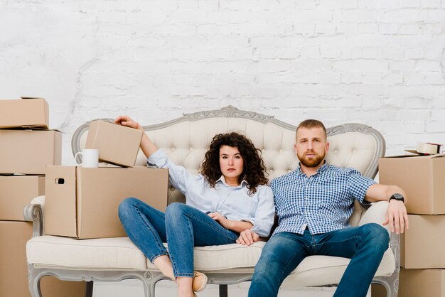 Couple sitting on sofa near carton boxes