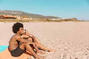 Free photo couple sitting together on beach