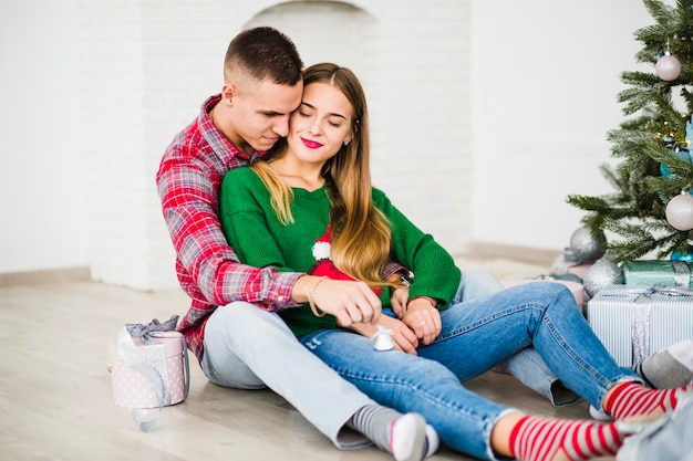 Couple sitting together next to christmas tree