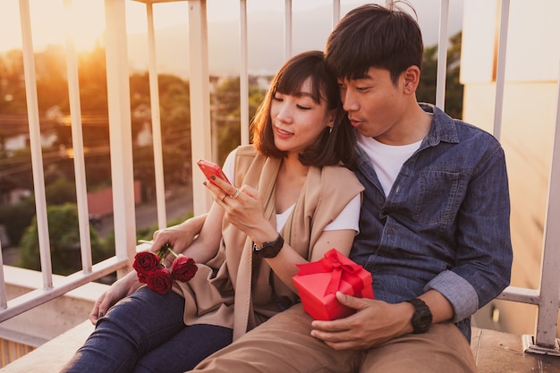 Couple sitting together with a red gift looking at the mobile