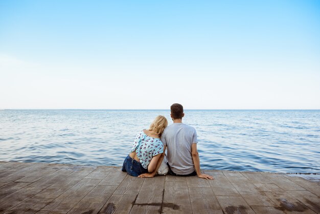 Couple sitting with French bulldog near sea