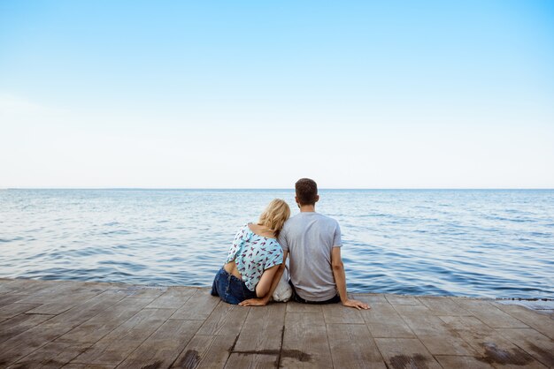 海のそばのフレンチブルドッグと座っているカップル