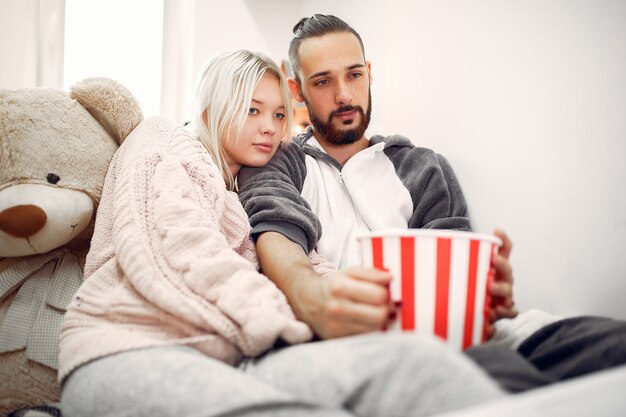 Couple sitting with popcorns and big teddy bear