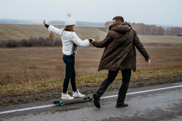 屋外でスケートボードをするカップル