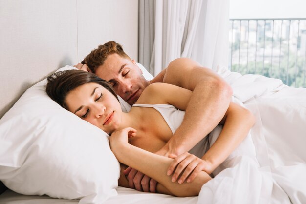 Couple sleeping and cuddling in bed