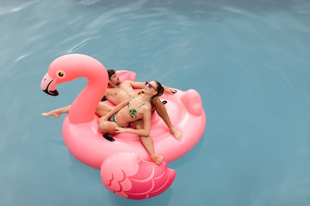 Couple sleeping together on a inflatable tube in swimming pool