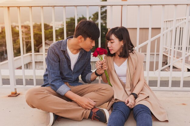 Couple smelling a rose sitting on the floor