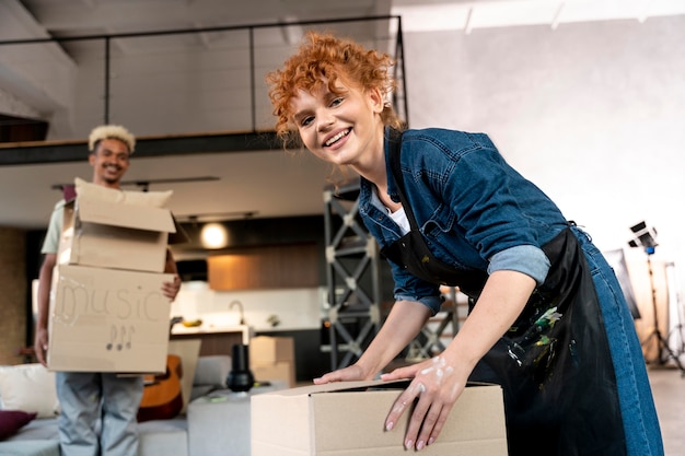 Couple sorting belongings from cardboard boxes after moving in new home