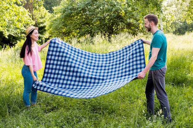 Couple spreading blanket for picnic
