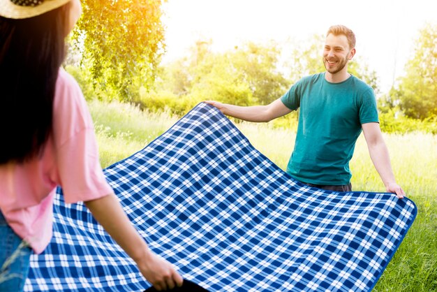 Couple spreading blue tablecloth for picnic