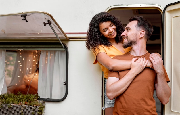 Free photo couple standing in front of camper van and looking at each other