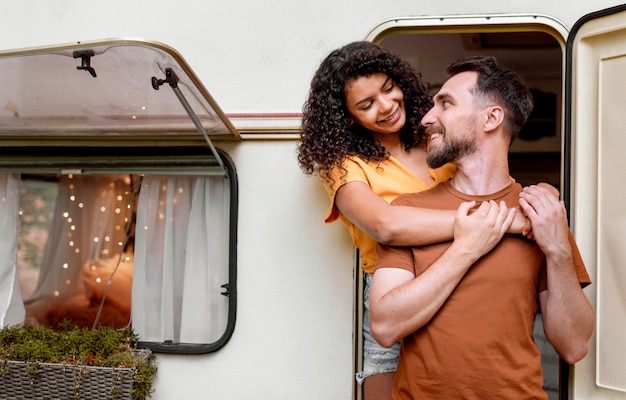 Couple standing in front of camper van and looking at each other