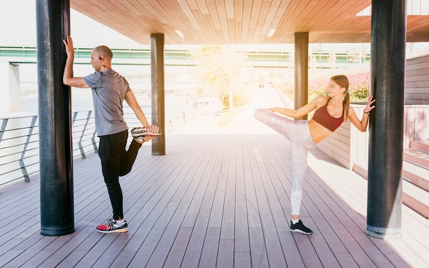 Free photo couple standing near the pillar stretching her leg while doing exercise