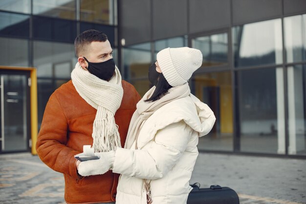 Couple standing outdoors wearing face mask and waiting for travel