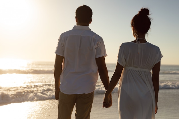 Couple standing together hand in hand on the beach