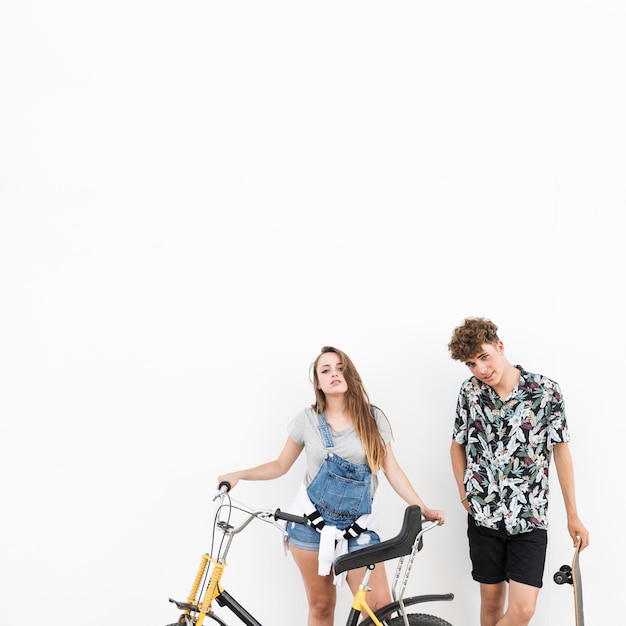 Couple standing with bicycle and skateboard on white background
