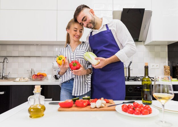 Couple standing with vegetables at table