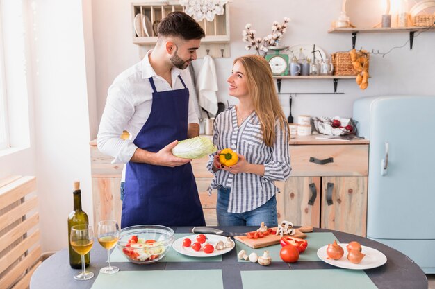 Couple standing with vegetables at table