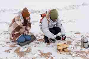 Free photo couple starting a fire on the beach during a winter road trip to warm up