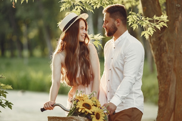 Couple in a summer park. People with vintage bicycle. Girl in a hat.