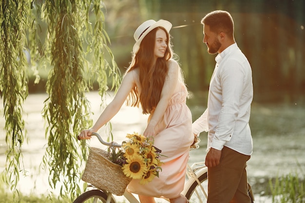 夏の公園のカップル。ビンテージ自転車を持つ人々。帽子の少女。