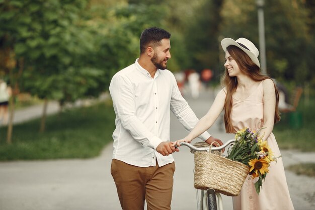 Couple in a summer park. People with vintage bicycle. Girl in a hat.