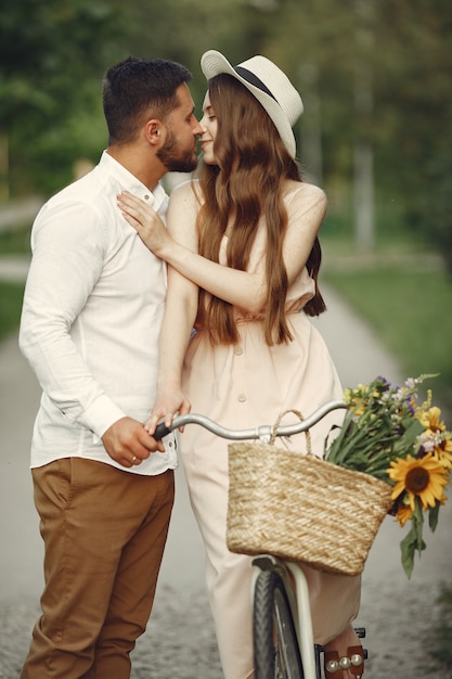 Couple in a summer park. People with vintage bicycle. Girl in a hat.