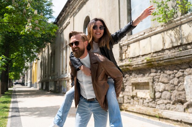 Couple in synthetic leather jackets piggyback riding outdoors