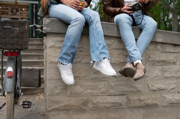 Couple in synthetic leather jackets sitting on concrete fence outdoors