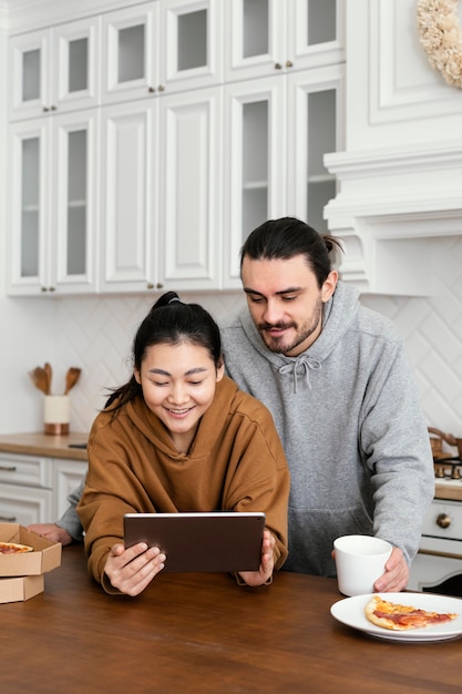 Бесплатное фото Пара завтракает на кухне и использует планшет