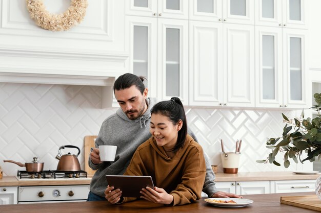 Couple taking morning meal in the kitchen and using a tablet