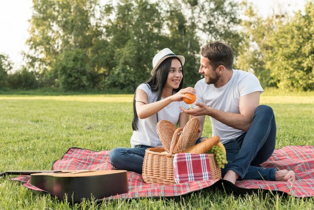 ピクニック毛布にオレンジを取ってカップル
