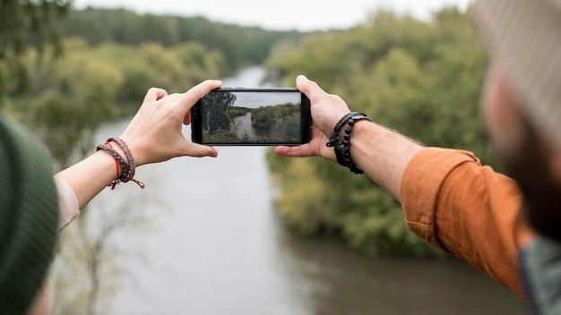 スマートフォンで自然の写真を撮るカップル
