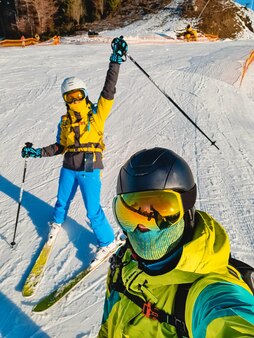 Пара, делающая селфи на склоне горнолыжного курорта в солнечный день, весело