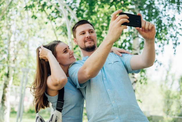 Foto gratuita coppie che prendono selfie nella foresta di betulle