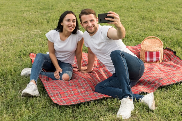 Coppie che prendono un selfie sulla coperta di picnic