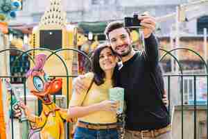 Free photo couple taking a selfie in a theme park