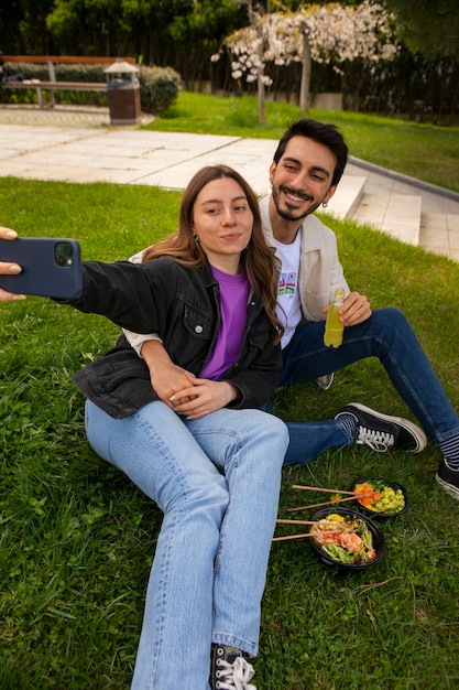 無料写真 芝生の上でサーモン丼を食べながら自撮りするカップル