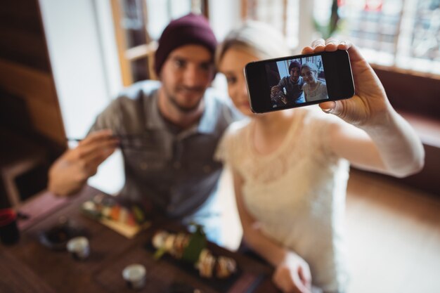 Couple taking selfie while having sushi