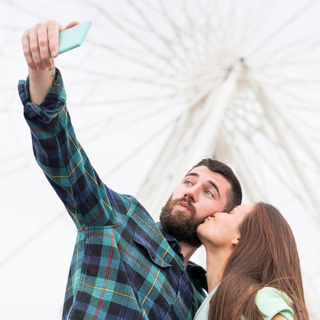 Couple taking selfie while kissing outdoors