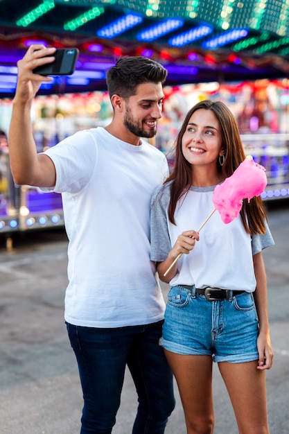 Бесплатное фото Пара, делающая селфи с розовой сладкой ватой